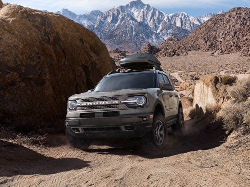 2024 Ford Bronco Sport driving up a rocky hill with mountains in the background