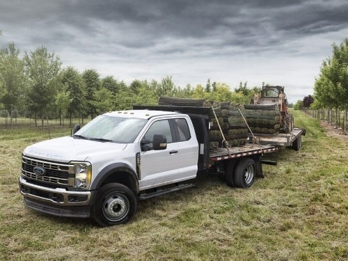 2024 Ford Chassis Cab towing two trailers with lumber and a tractor