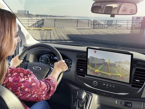 2024 Ford Transit view of woman using rear camera to back into a parking spot